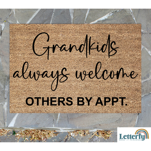 Doormat with text 'Grandkids always welcome others by appt.' on a stone floor.